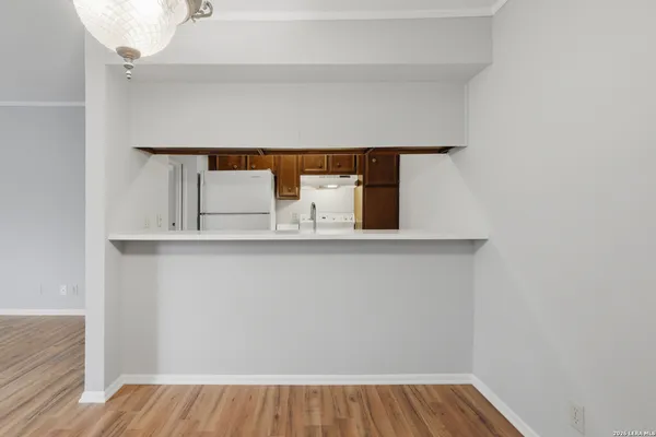 an empty room with wooden floor cabinet and windows