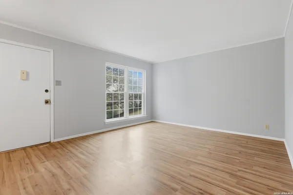 a view of an empty room with wooden floor and a window