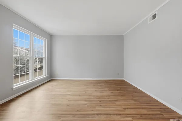 a view of an empty room with wooden floor and a window