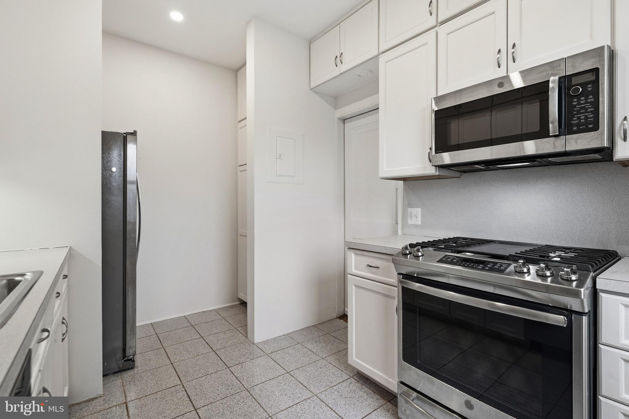 4000 Cathedral Avenue Northwest, Unit 334B/335B Washington, DC 20016 - Photo 8 of 32 a kitchen with stainless steel appliances a stove a microwave and cabinets