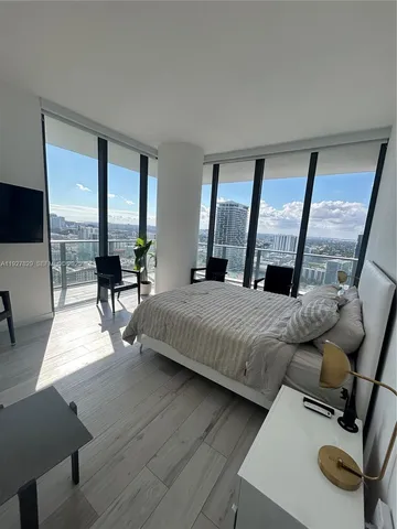 a bedroom with a bed and large windows