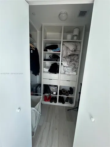 a view of walk in closet with clothes and shoes