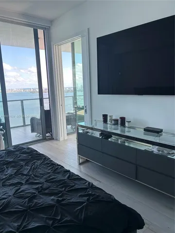 a spacious bedroom with a bed and a flat tv screen next to a window