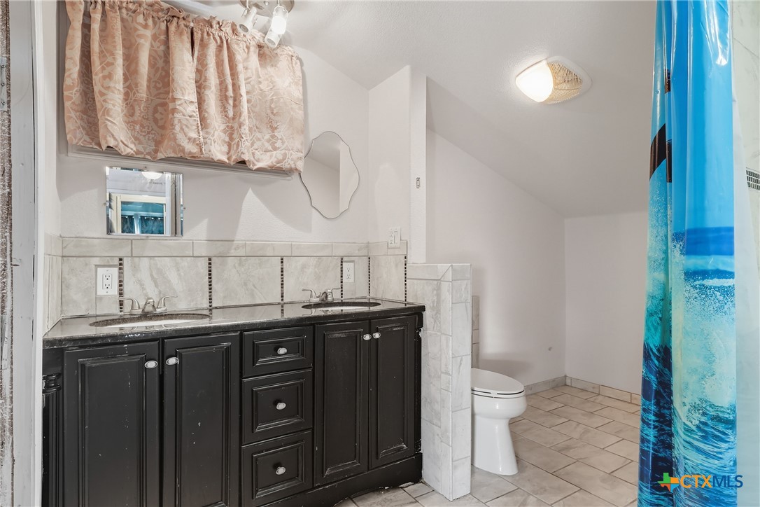 488 Alamo Beach Avenue Port Lavaca, TX 77979 - Photo 25 of 36 a bathroom with a granite countertop sink a toilet and a mirror