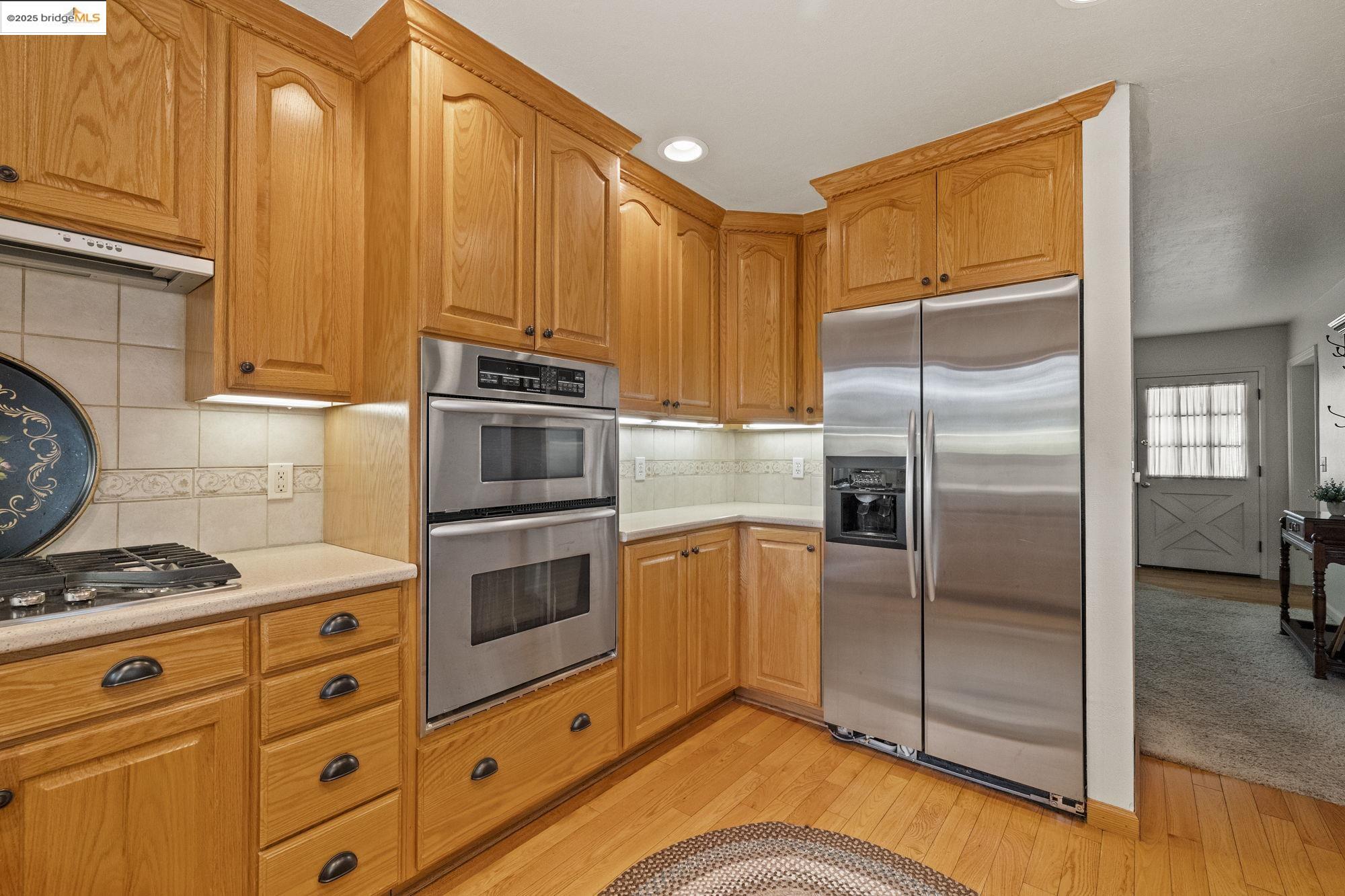 21645 La Vereda Road Sonora, CA 95370 - Photo 11 of 32 a kitchen with stainless steel appliances granite countertop a refrigerator a stove and a sink with wooden floor