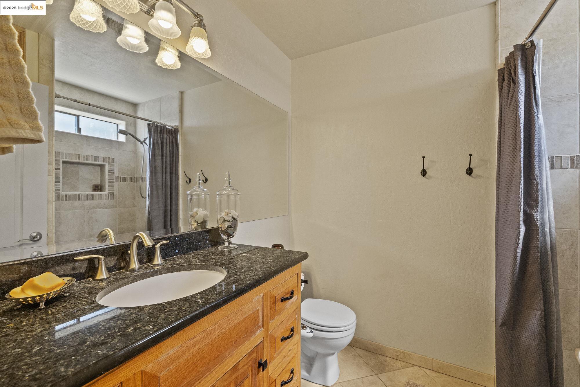 21645 La Vereda Road Sonora, CA 95370 - Photo 21 of 32 a bathroom with a granite countertop sink a toilet and a mirror