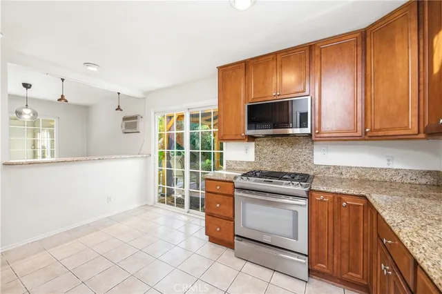 a kitchen with granite countertop a stove top oven microwave and cabinets