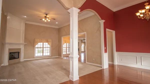 a view of an empty room with chandelier fan and fire place