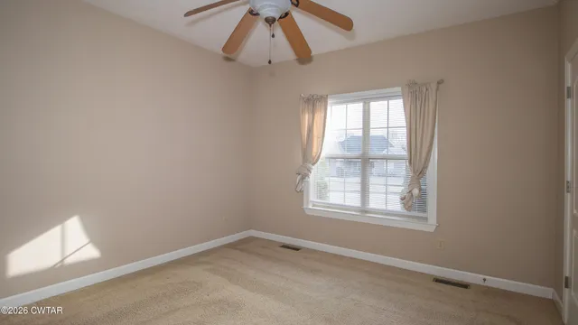 an empty room with a window and a fan