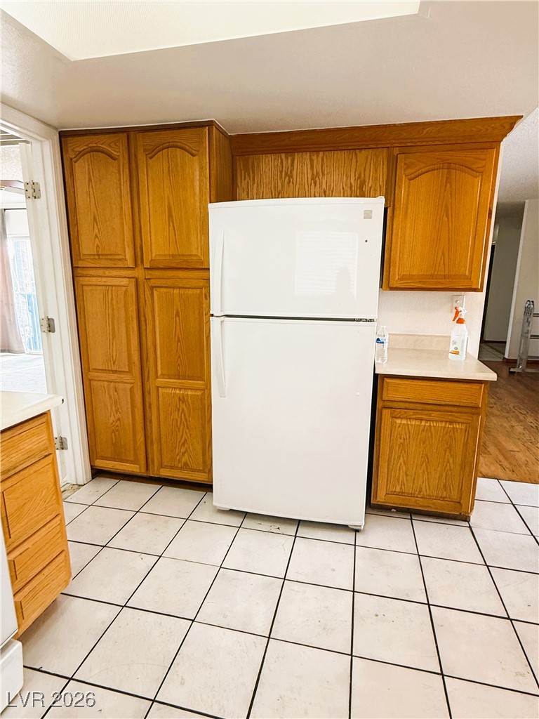 5311 South Sandhill Road Las Vegas, NV 89120 - Photo 11 of 24 Kitchen featuring brown cabinetry, freestanding refrigerator, light countertops, and light tile patterned floors
