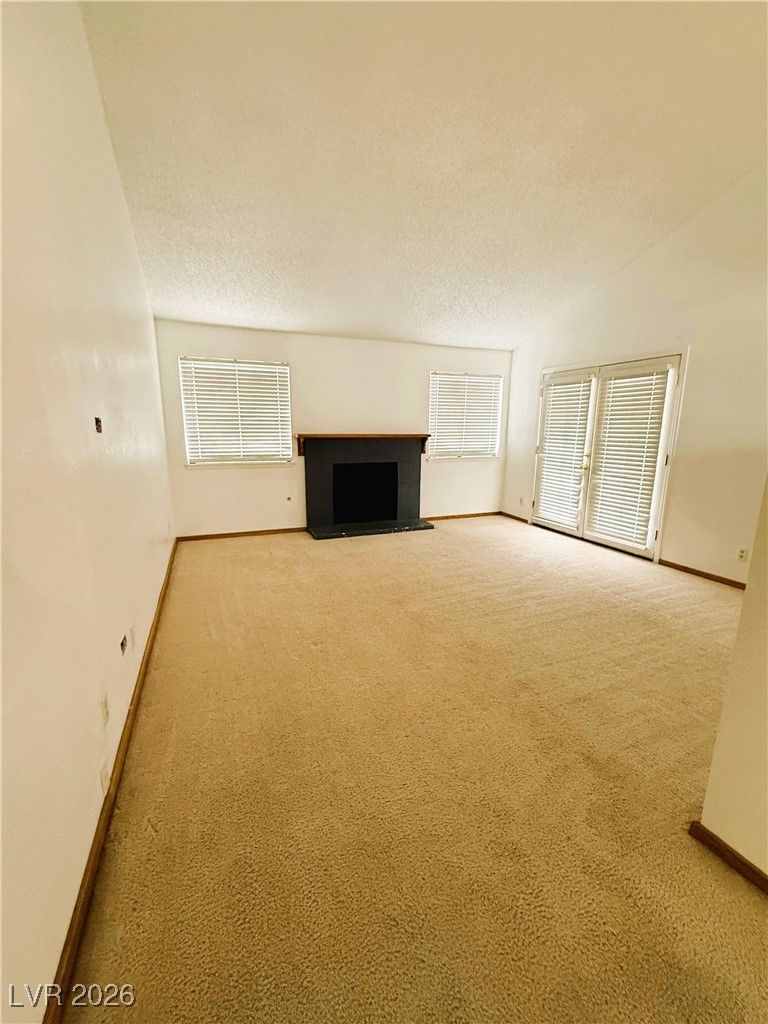 5311 South Sandhill Road Las Vegas, NV 89120 - Photo 15 of 24 Unfurnished living room featuring a fireplace, carpet flooring, and a towering ceiling