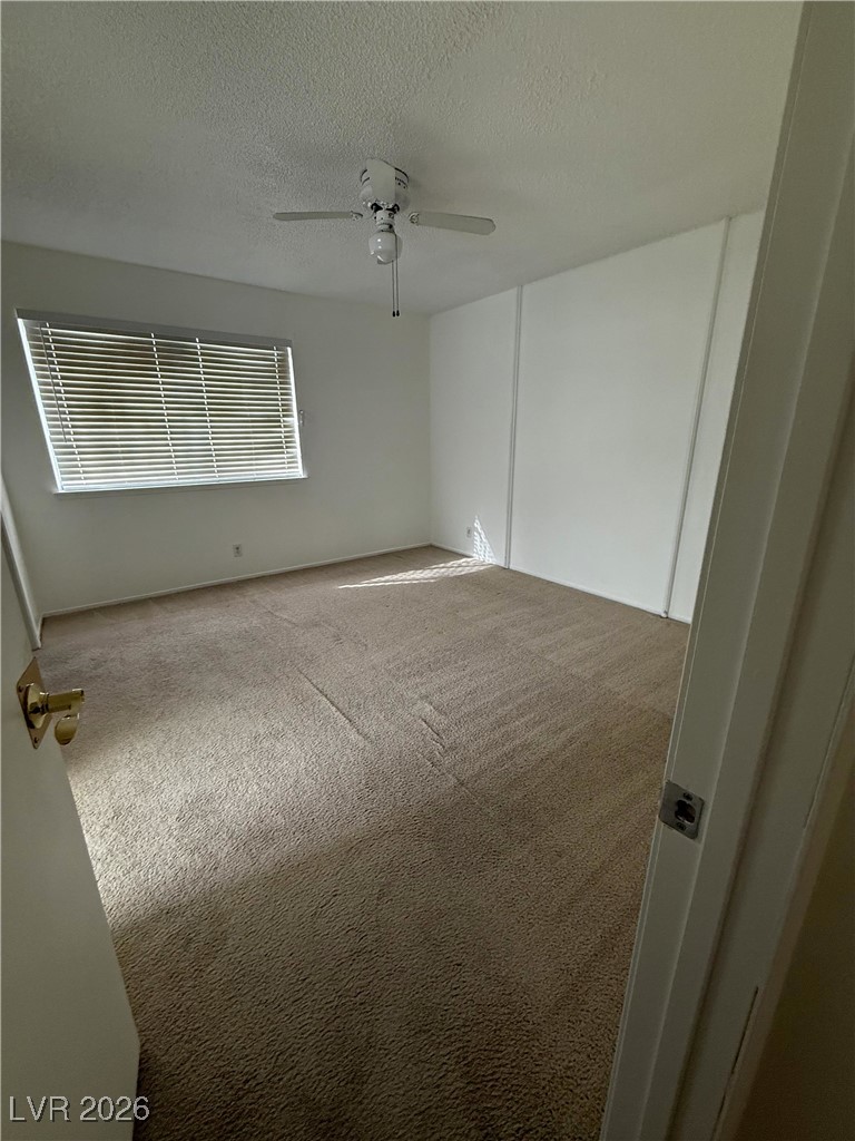 5311 South Sandhill Road Las Vegas, NV 89120 - Photo 4 of 24 Empty room featuring a textured ceiling, carpet, and a ceiling fan