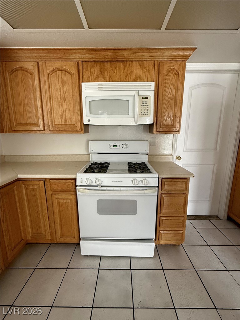 5311 South Sandhill Road Las Vegas, NV 89120 - Photo 10 of 24 Kitchen with white appliances, light countertops, light tile patterned floors, and brown cabinetry