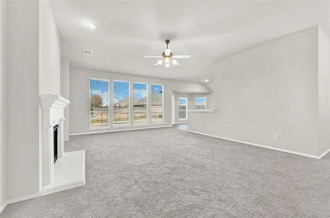 an empty room with windows and fireplace