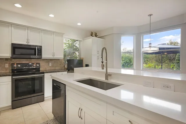 a kitchen with stainless steel appliances granite countertop a sink a stove and a refrigerator