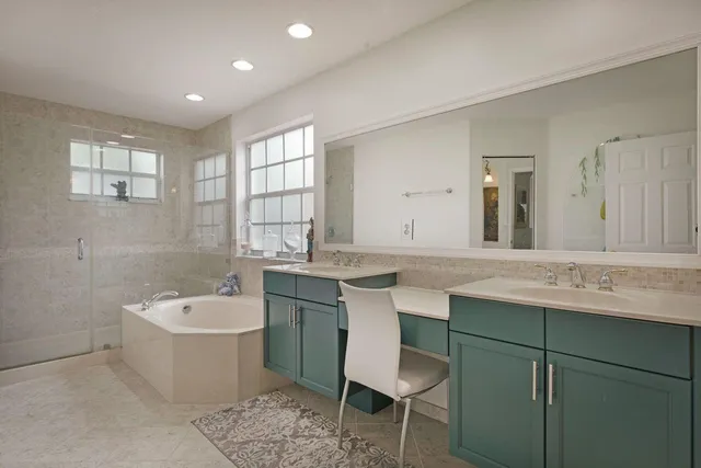 a bathroom with a double vanity sink mirror and bathtub
