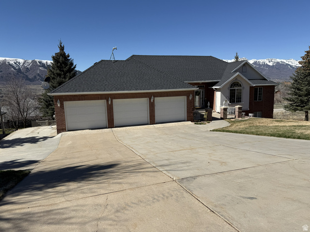 4117 North Wolf Ridge Circle Eden, UT 84310 - Photo 32 of 33 Ranch-style home featuring a mountain view, concrete driveway, brick siding, an attached garage, and a shingled roof