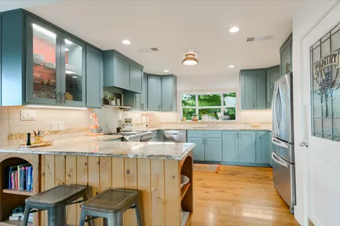a kitchen with kitchen island granite countertop a stove a sink and a refrigerator