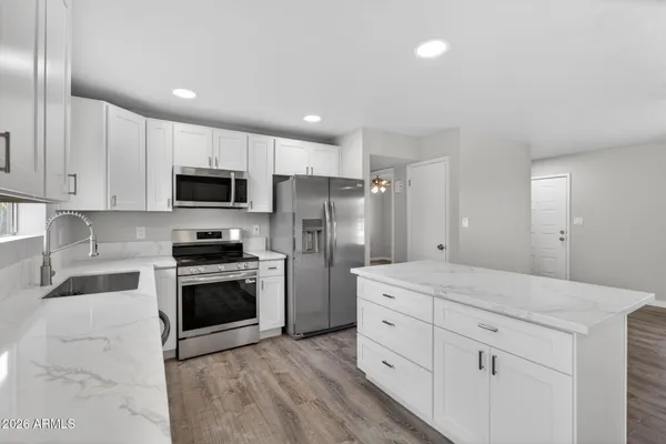 a kitchen with a sink white cabinets and stainless steel appliances