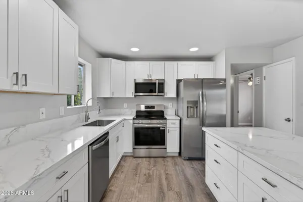 a kitchen with a sink stove a refrigerator and white cabinets