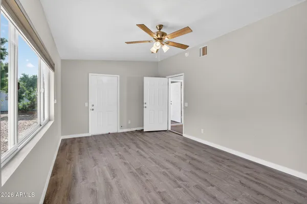 a view of an empty room with wooden floor and a window