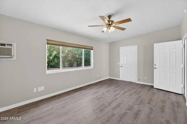 an empty room with wooden floor fan and windows