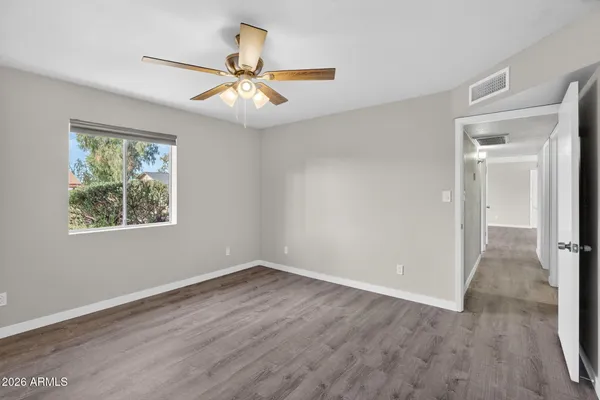 a view of an empty room with wooden floor and a window