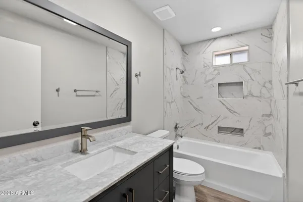 a bathroom with a granite countertop sink a toilet and a bathtub