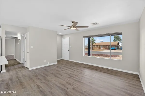 a view of an empty room with a window and wooden floor