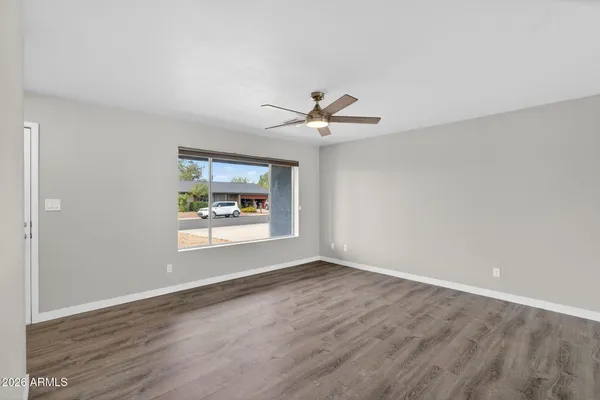 a view of an empty room with wooden floor and a window