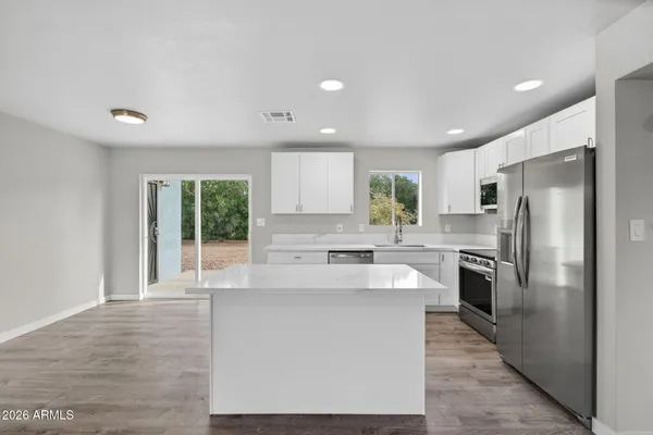 a large kitchen with stainless steel appliances a large window in it and a refrigerator