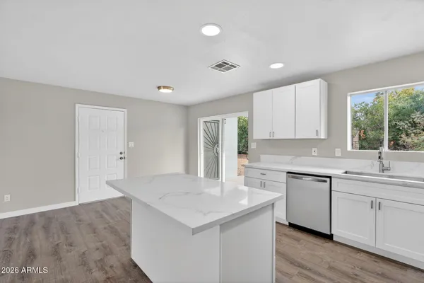 a kitchen with a sink dishwasher a stove and white cabinets with wooden floor