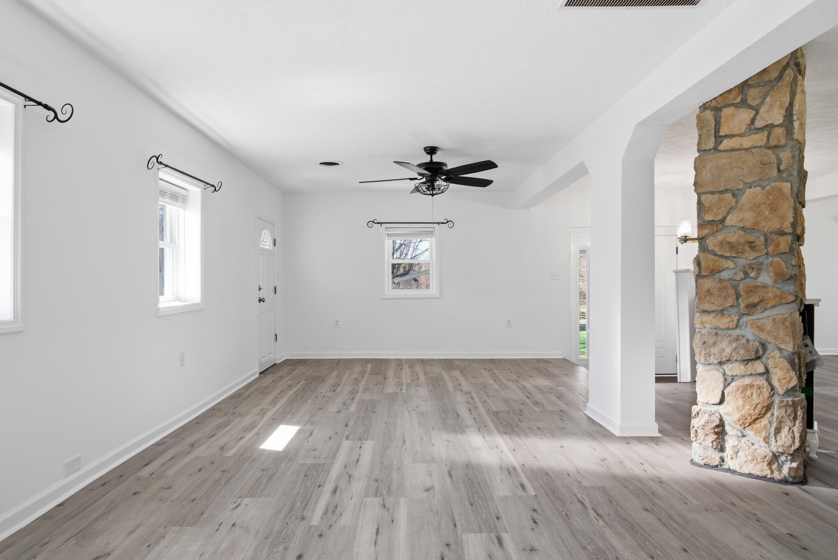 6458 Piney Woods Road Riner, VA 24149 - Photo 5 of 50 an empty room with wooden floor a ceiling fan and windows