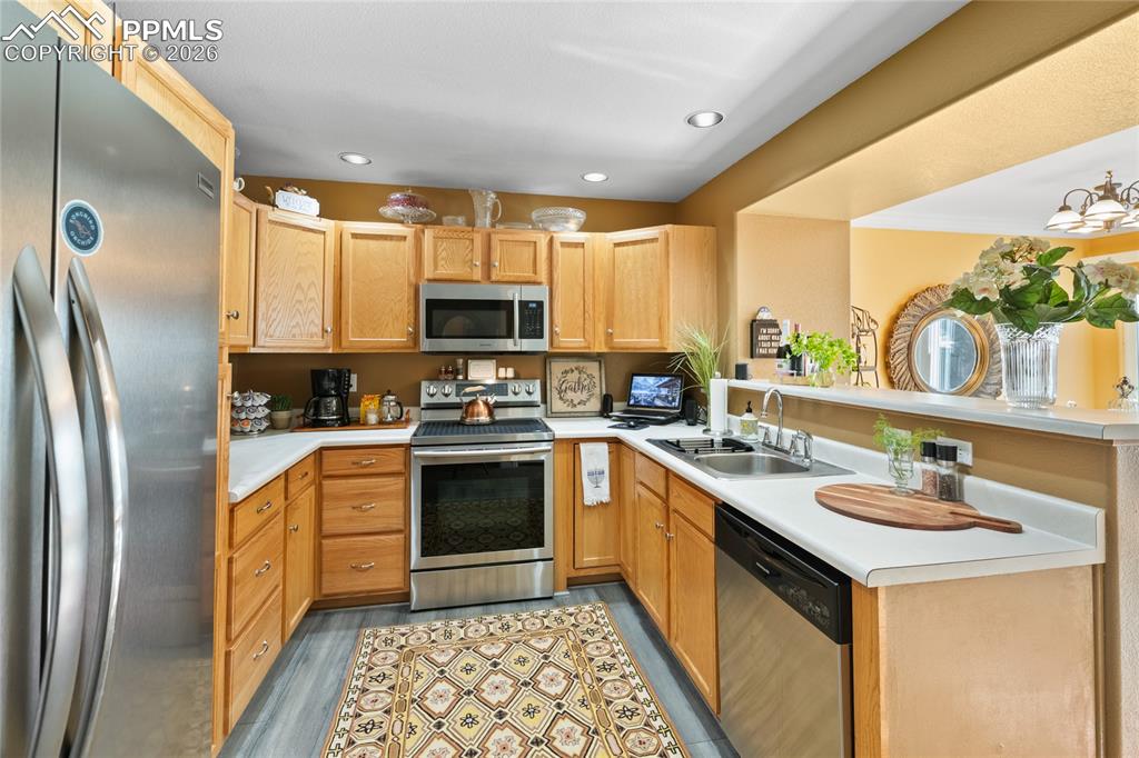 5639 Sunshade Point Colorado Springs, CO 80923 - Photo 12 of 36 a kitchen with stainless steel appliances granite countertop a sink a stove a refrigerator and a microwave