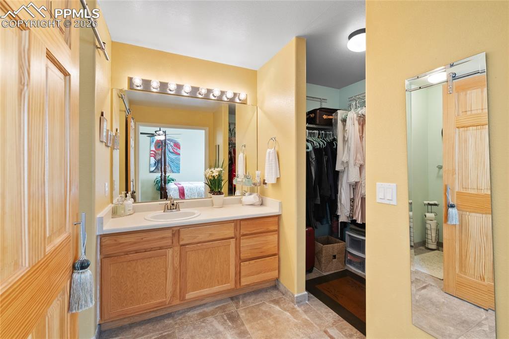 5639 Sunshade Point Colorado Springs, CO 80923 - Photo 20 of 36 a en suite bathroom with a shower sink and mirror