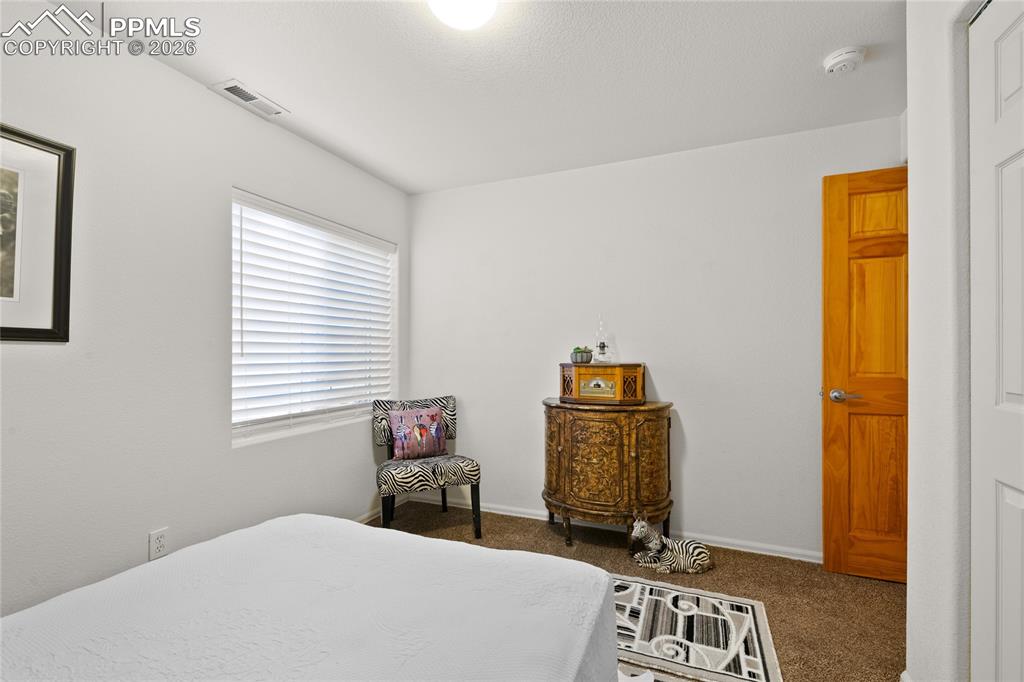 5639 Sunshade Point Colorado Springs, CO 80923 - Photo 33 of 36 a bedroom with a bed and wooden floor