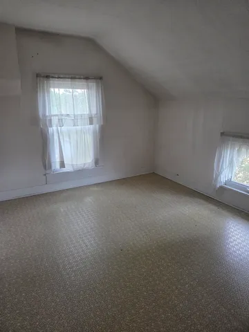 an empty room with a fireplace and windows