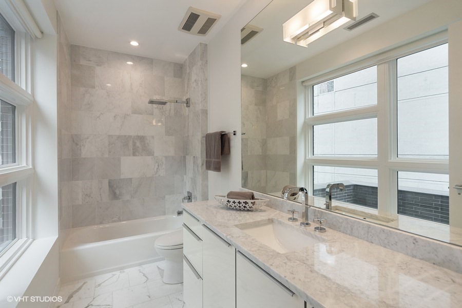 1011 North Dearborn Street Chicago, IL 60610 - Photo 21 of 33 a bathroom with a granite countertop sink a large mirror and a bathtub