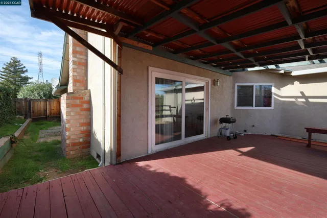 a patio with table and chairs with wooden floor and fence