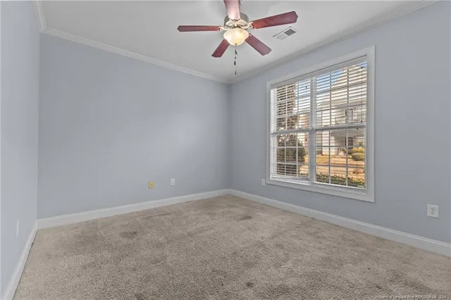 an empty room with chandelier fan and windows