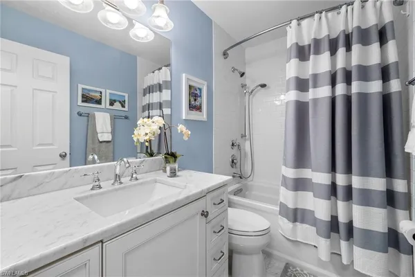 a bathroom with a sink a toilet a shower curtain and a mirror