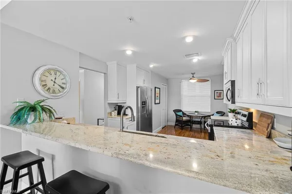 a kitchen with stainless steel appliances kitchen island granite countertop a sink and a refrigerator