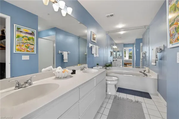 a bathroom with a double vanity sink a large mirror and a bathtub