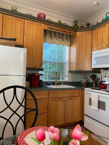 a kitchen with stainless steel appliances wooden cabinets a stove a sink and a large window