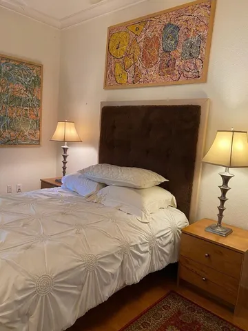 a bedroom with a bed and painting on the wall