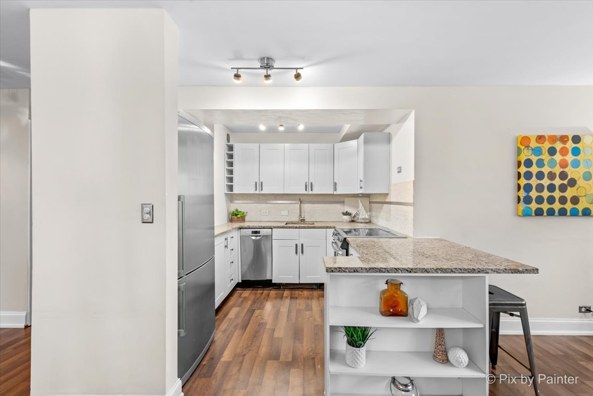 2909 North Sheridan Road, Unit 1507 Chicago, IL 60657 - Photo 7 of 27 a large white kitchen with a sink and wooden floor