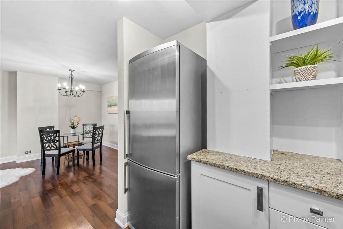2909 North Sheridan Road, Unit 1507 Chicago, IL 60657 - Photo 9 of 27 a kitchen with granite countertop a refrigerator and a table chair