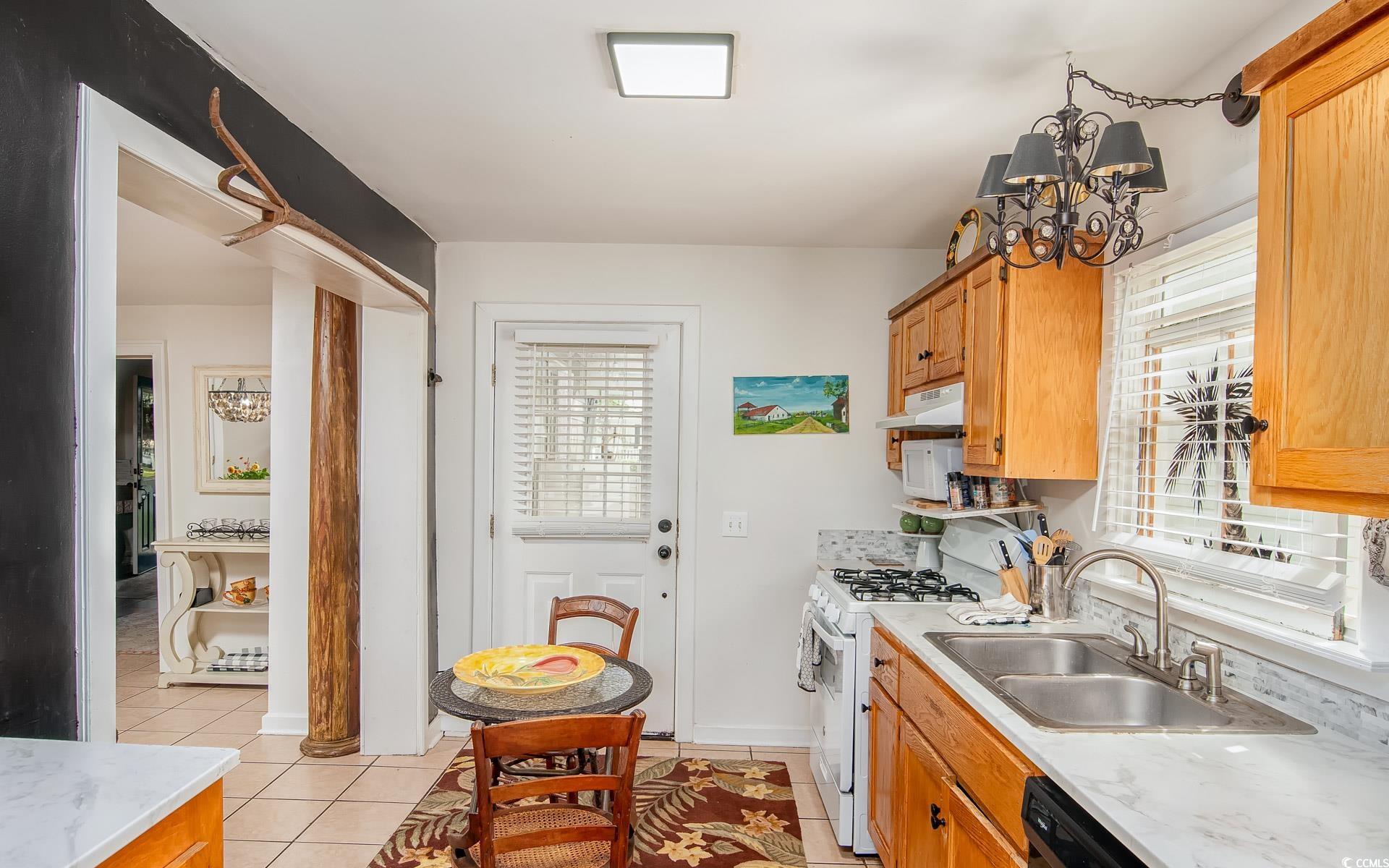 423 Highmarket Street Georgetown, SC 29440 - Photo 11 of 25 Kitchen featuring light countertops, white gas range, light tile patterned floors, under cabinet range hood, and a chandelier