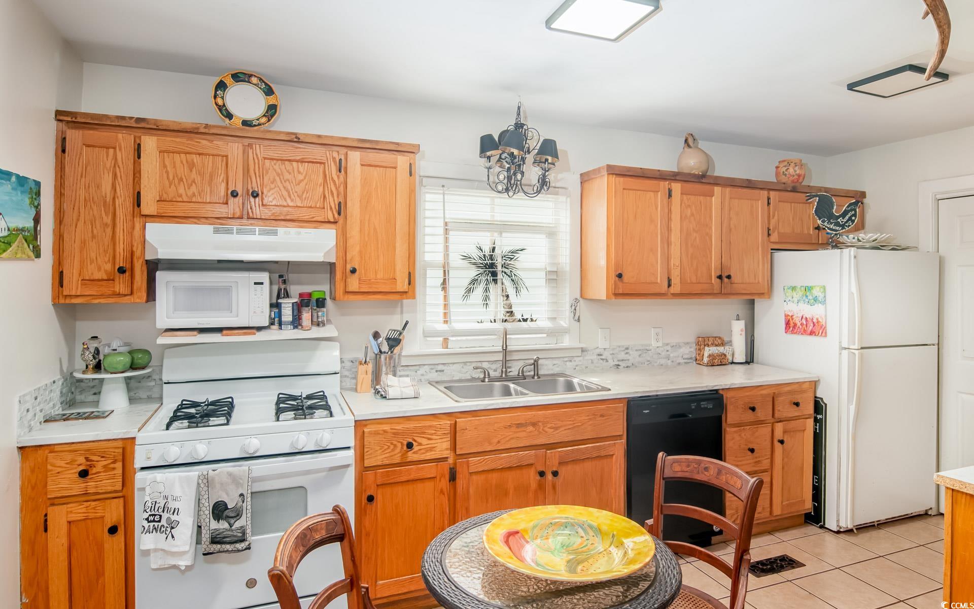 423 Highmarket Street Georgetown, SC 29440 - Photo 10 of 25 Kitchen with white appliances, light countertops, under cabinet range hood, light tile patterned floors, and brown cabinetry