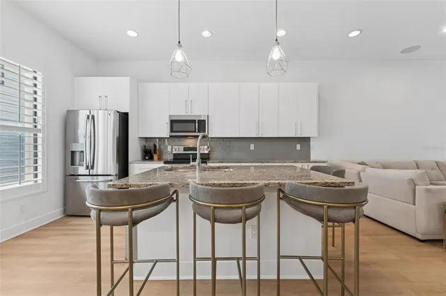 a kitchen with stainless steel appliances granite countertop a stove a refrigerator and a refrigerator with wooden floor